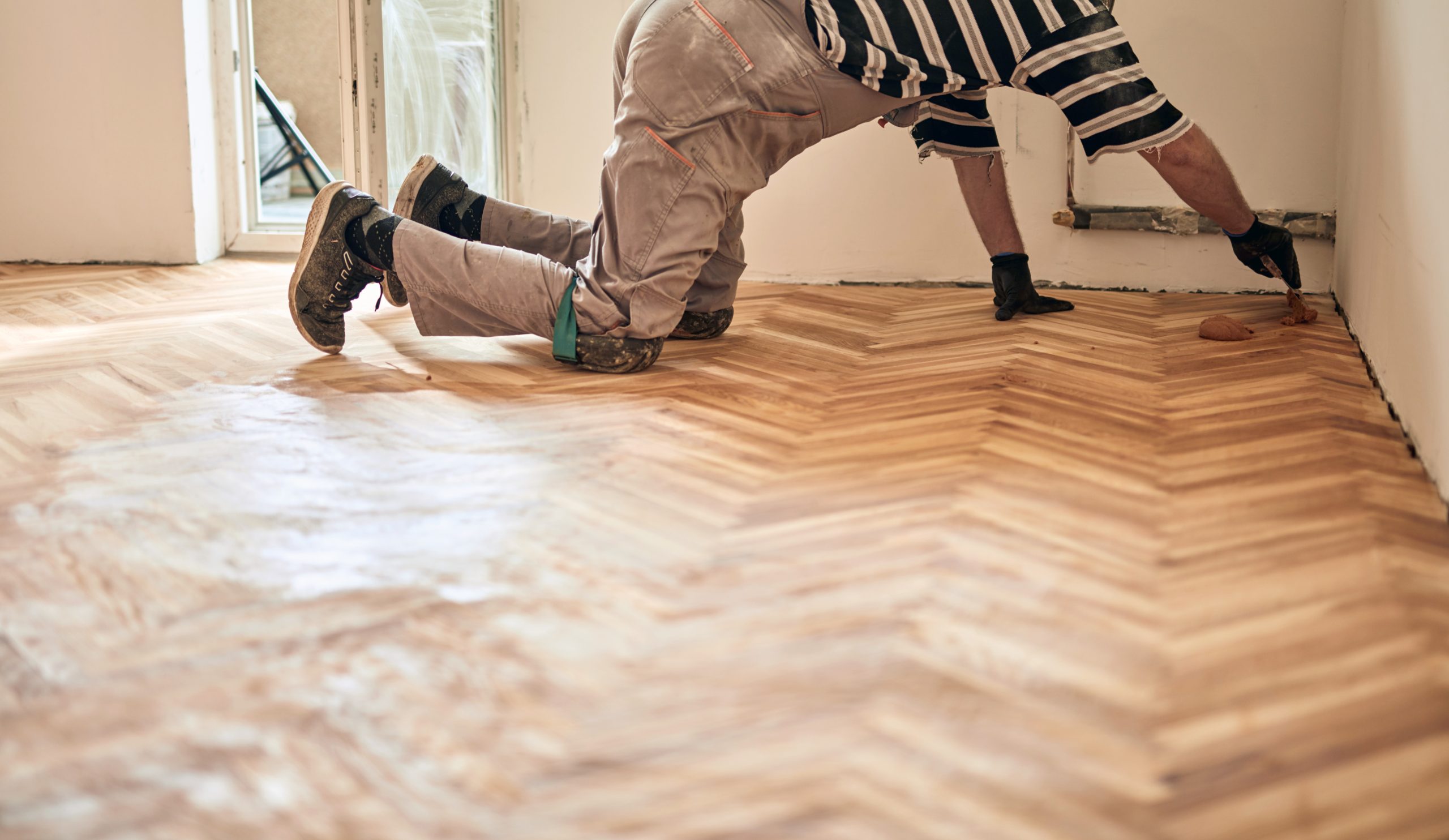 Sanding Parquet Floors in Sydenham – technician detailing the edges of a herringbone oak parquet (solid wood) after machine sanding.