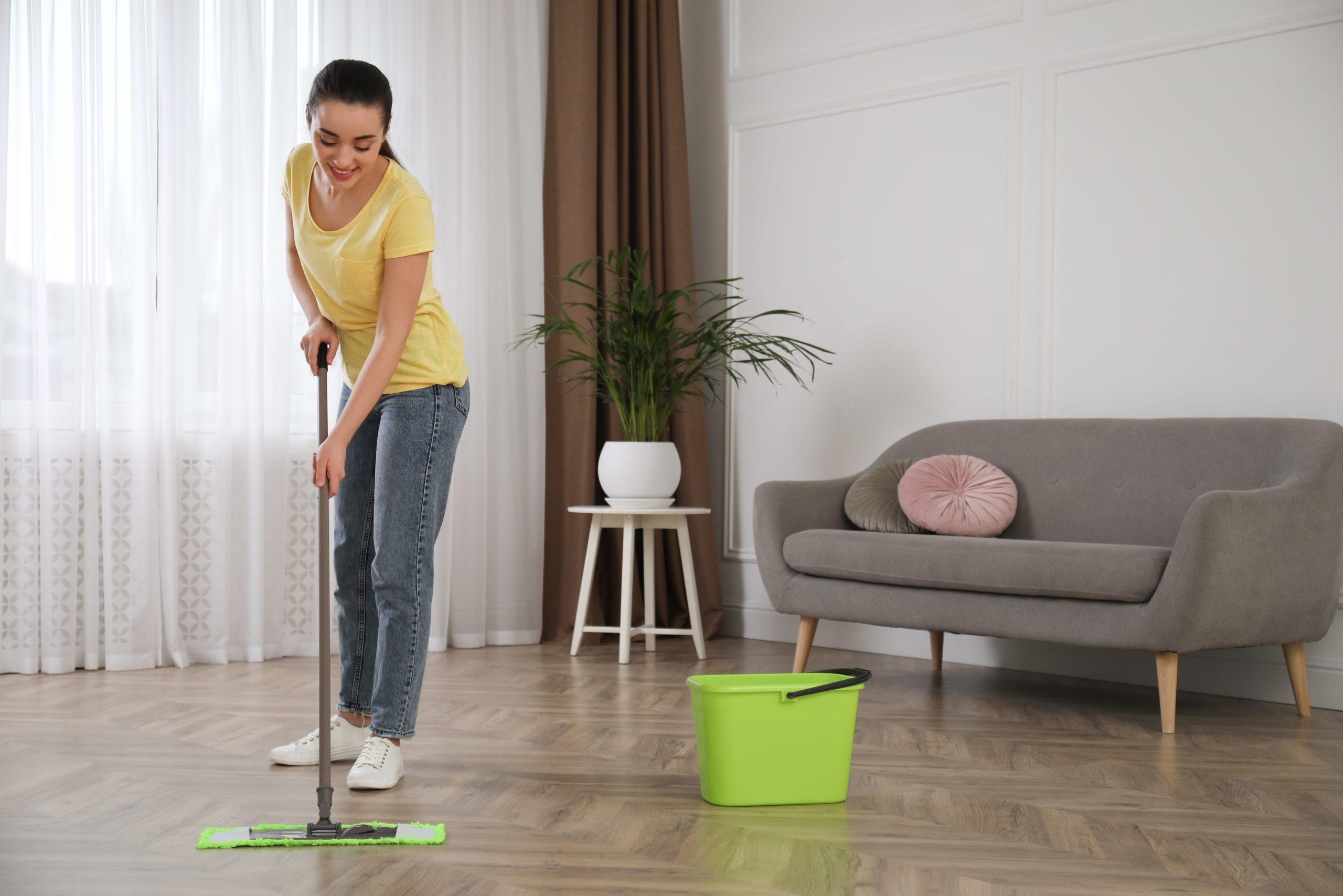 Sanding Parquet Floors in Sydenham – homeowner using a microfibre mop to maintain a freshly restored herringbone oak parquet floor after finishing.