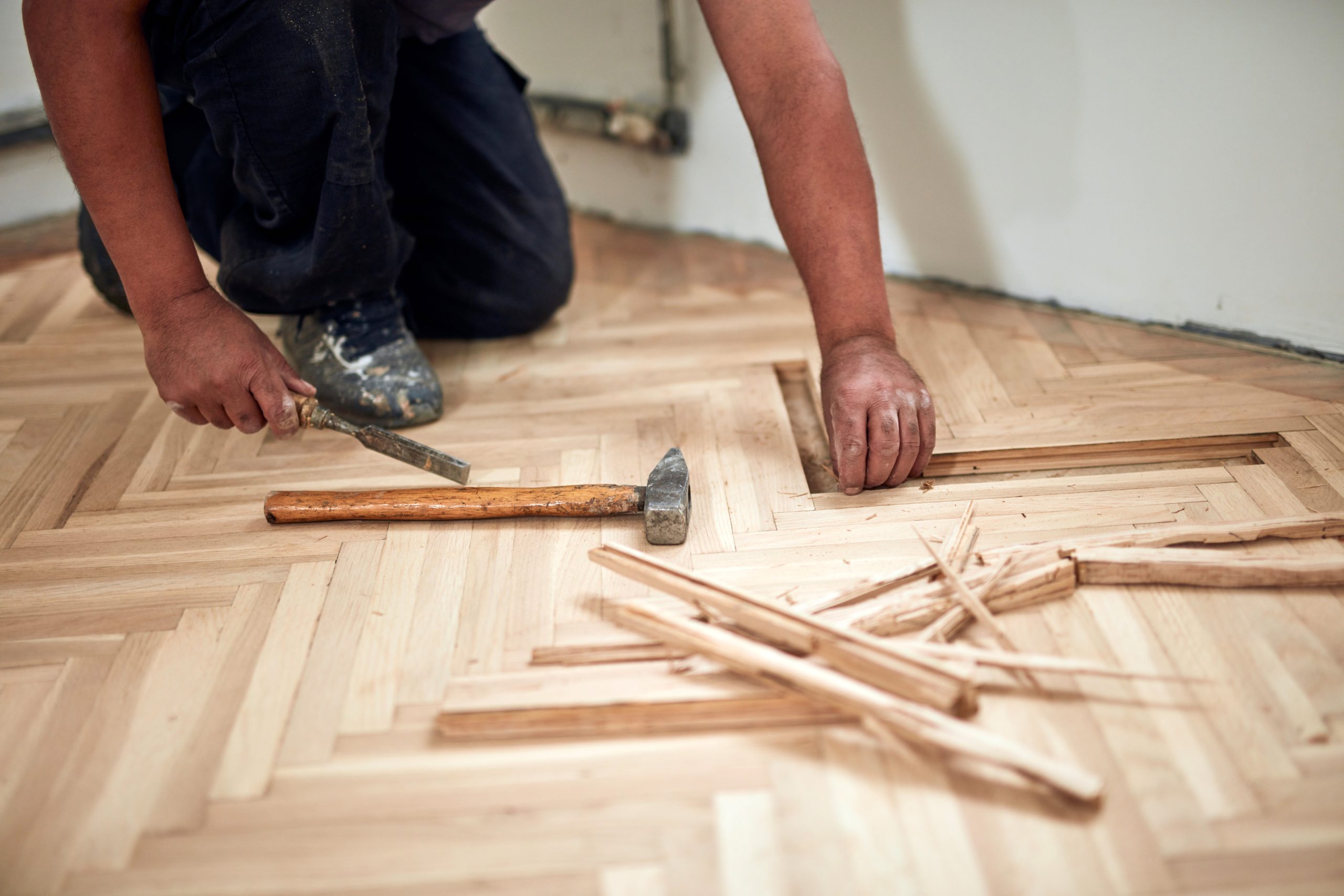 Sanding Parquet Floors in Sydenham – technician replacing damaged herringbone oak parquet blocks with chisel and mallet before machine sanding.