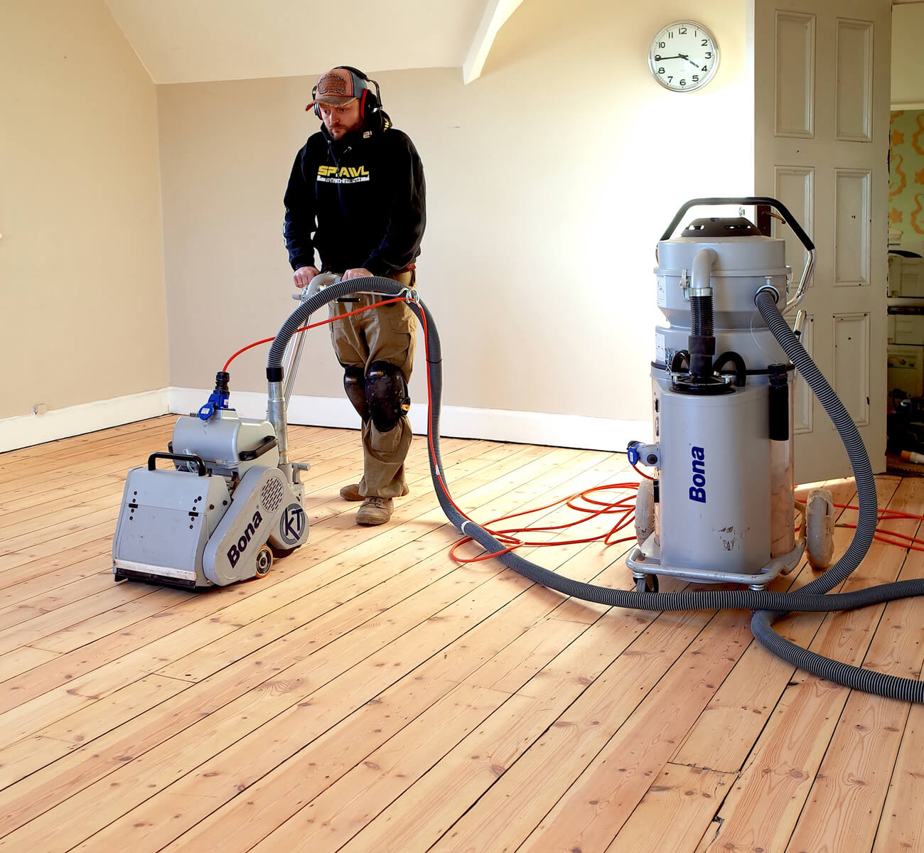 Wood Floor Sanding in Sydenham on softwood pine floorboards, with a technician using a dust-free Bona sanding machine in an empty room.