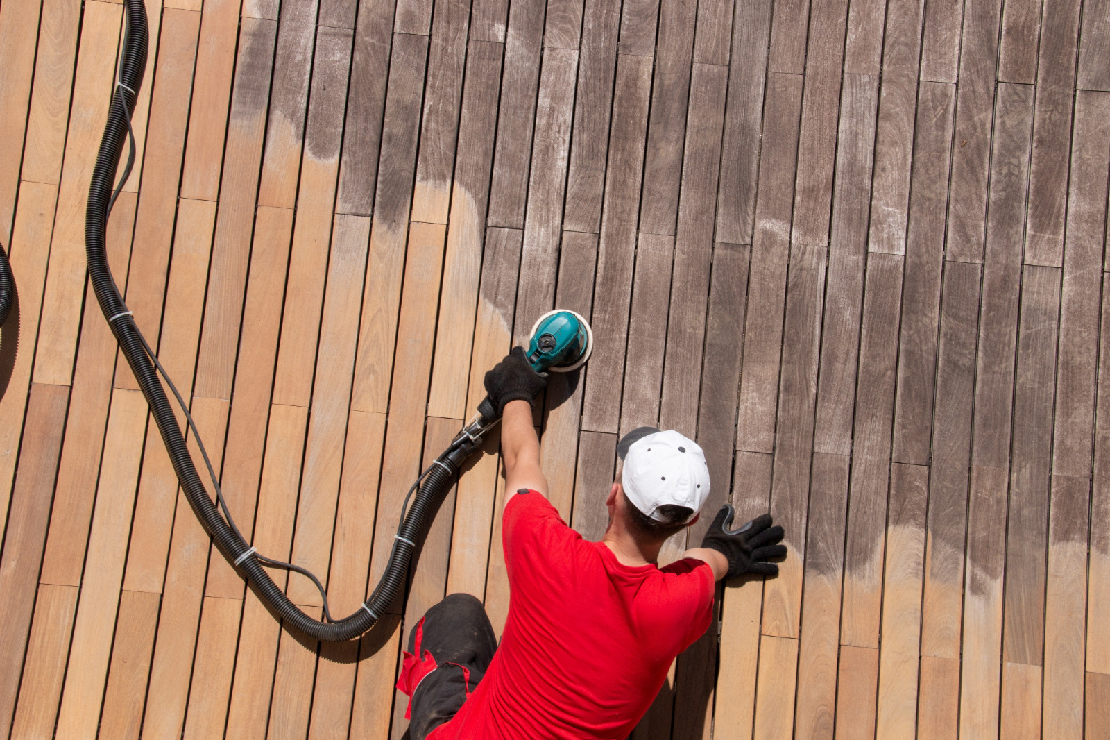 Wood Floor Sanding in Sydenham on a hardwood timber garden deck, with a technician using a hand sander to strip the grey, weathered decking boards back to fresh wood.