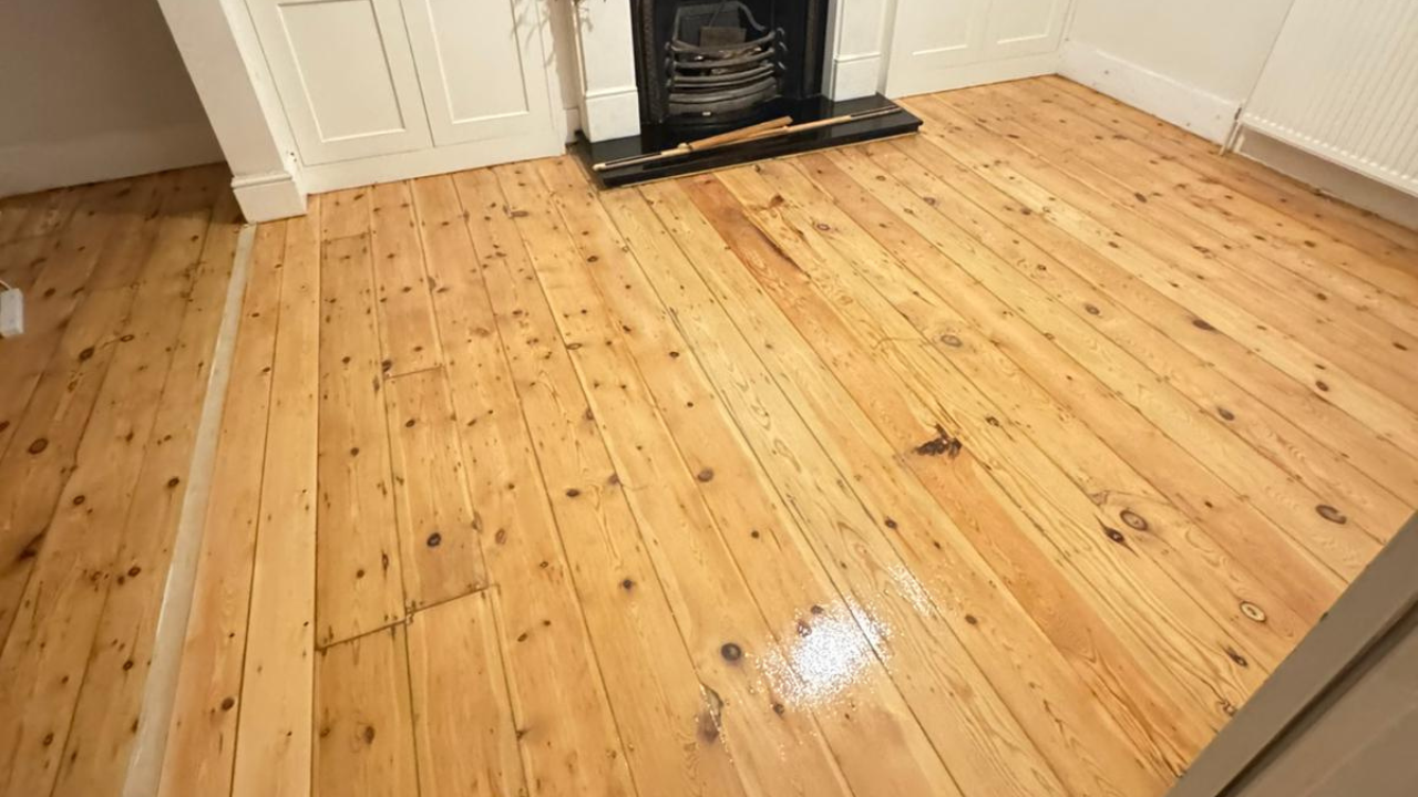 Wood Floor Sanding in Sydenham on softwood pine floorboards in a living room, showing a freshly sanded and sealed floor around a fireplace.