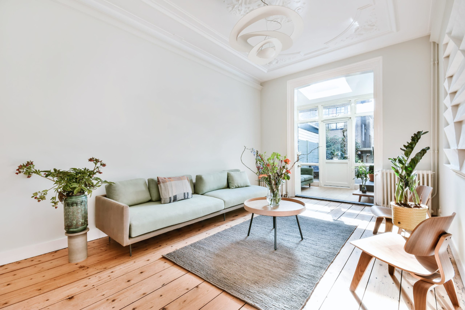 Bright Sydenham living room with softwood pine floorboards beautifully restored by Wood Floor Sanding, featuring modern furniture and large patio doors.