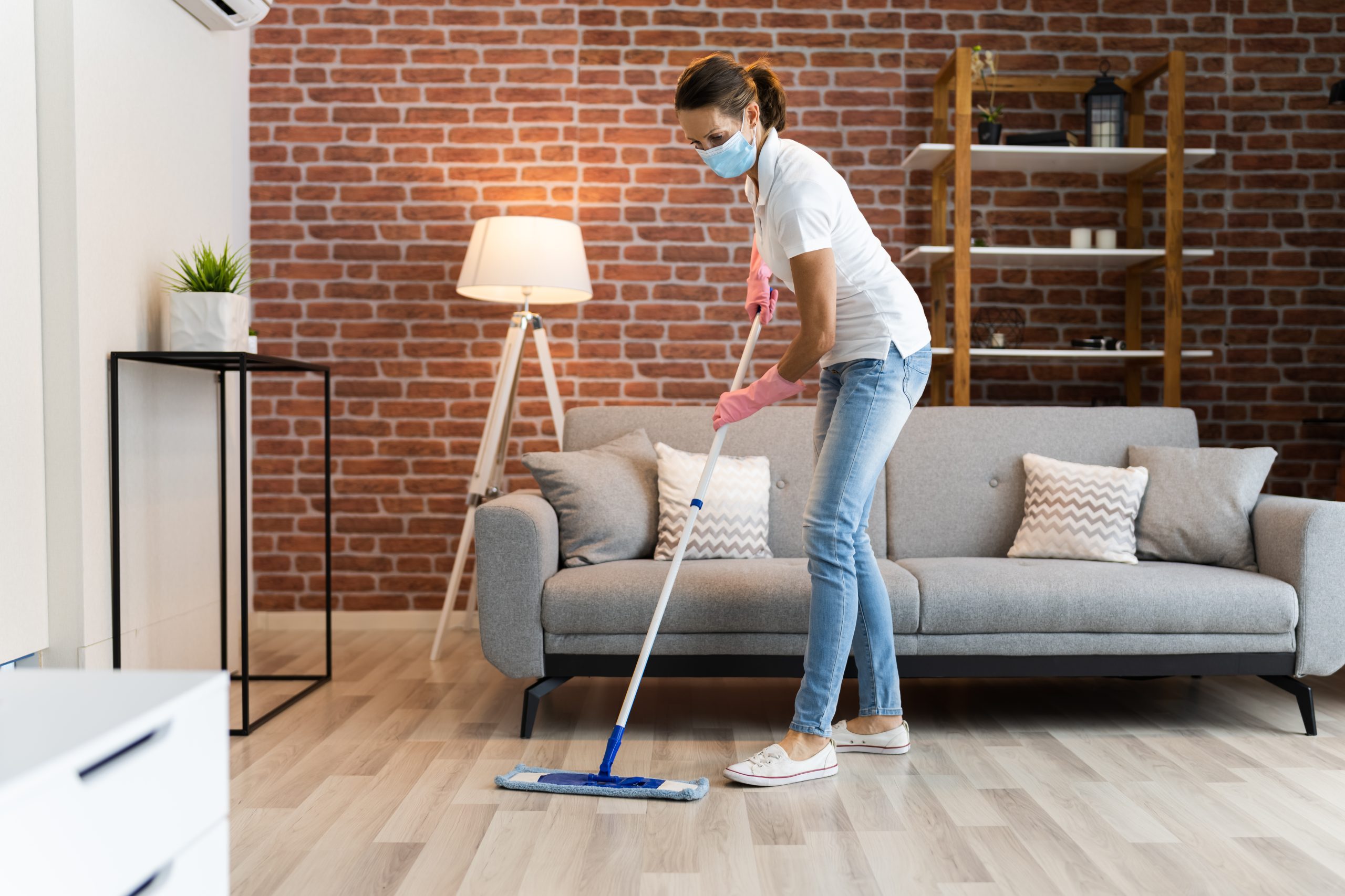 Hardwood Floor Refinishing in Sydenham with a woman mopping a light engineered oak plank hardwood living room floor as part of simple aftercare.