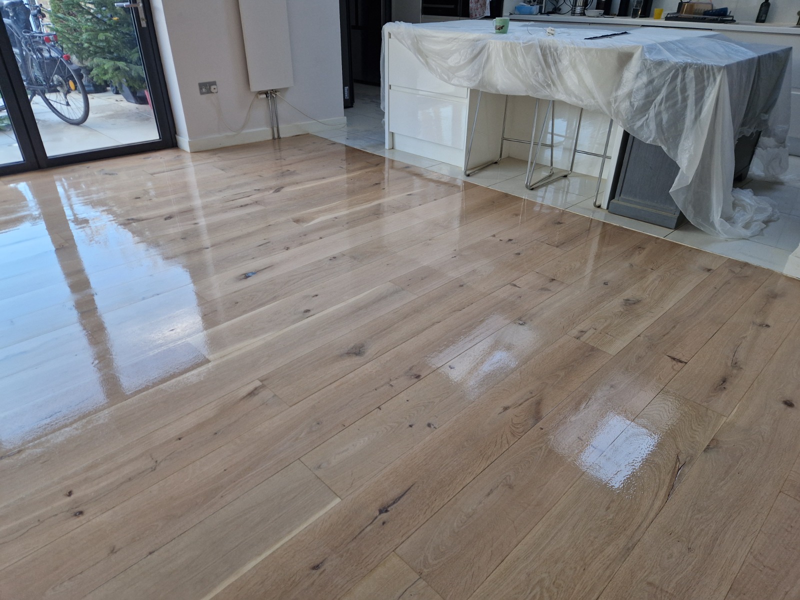 Hardwood Floor Refinishing in Sydenham showing a newly lacquered engineered oak plank kitchen-diner floor with a smooth, glossy finish.