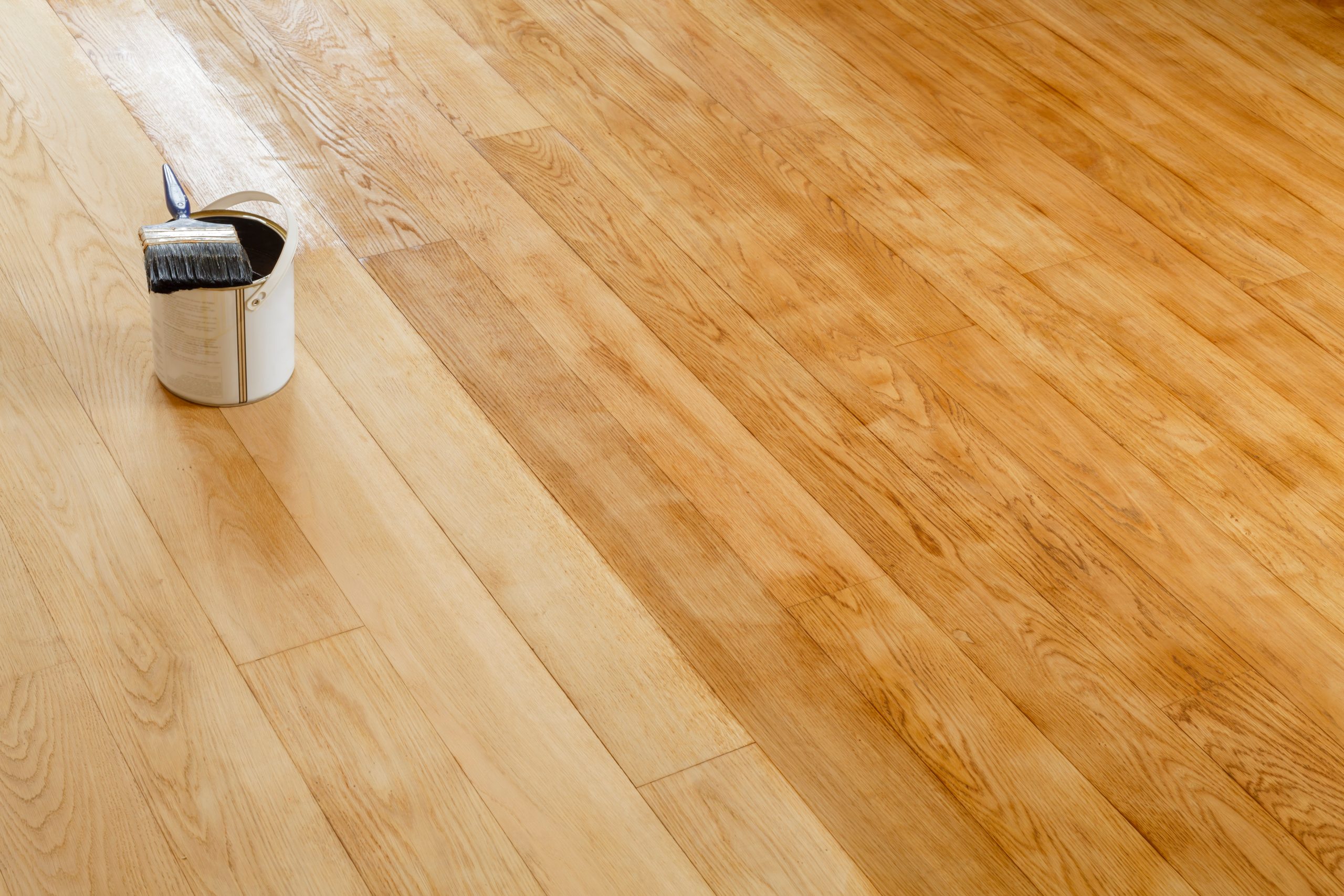 Hardwood Floor Refinishing in Sydenham with a brush and tin on European oak plank hardwood floor showing fresh oil finish being applied across the boards.