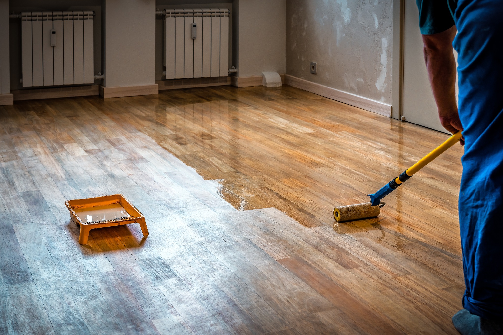 Hardwood Floor Refinishing in Sydenham with lacquer being rolled onto an oak hardwood living room floor, transforming the boards to a rich glossy finish.
