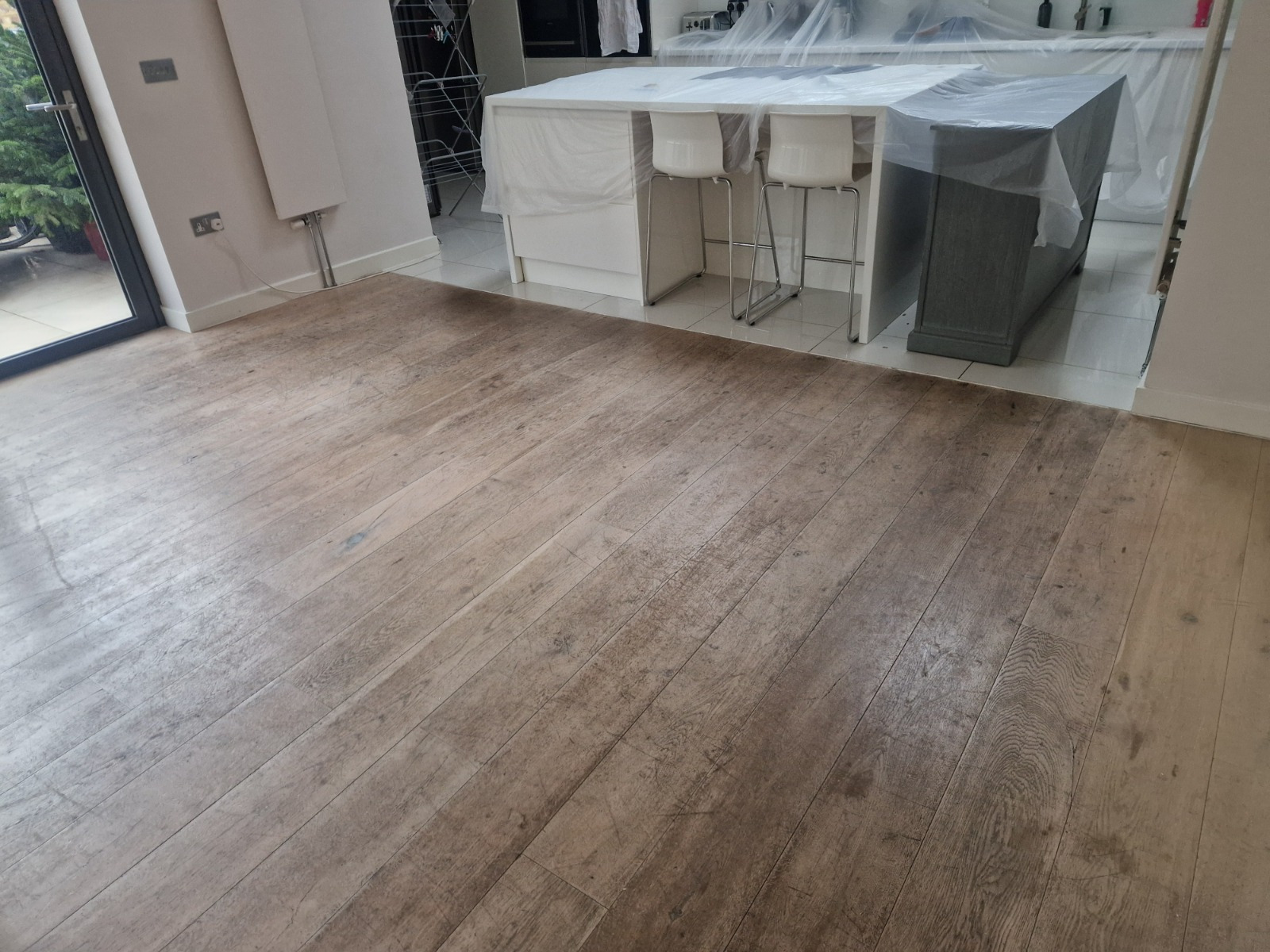 Hardwood Floor Refinishing in Sydenham showing a wide plank oak hardwood kitchen floor before restoration, with worn, faded and scratched boards.